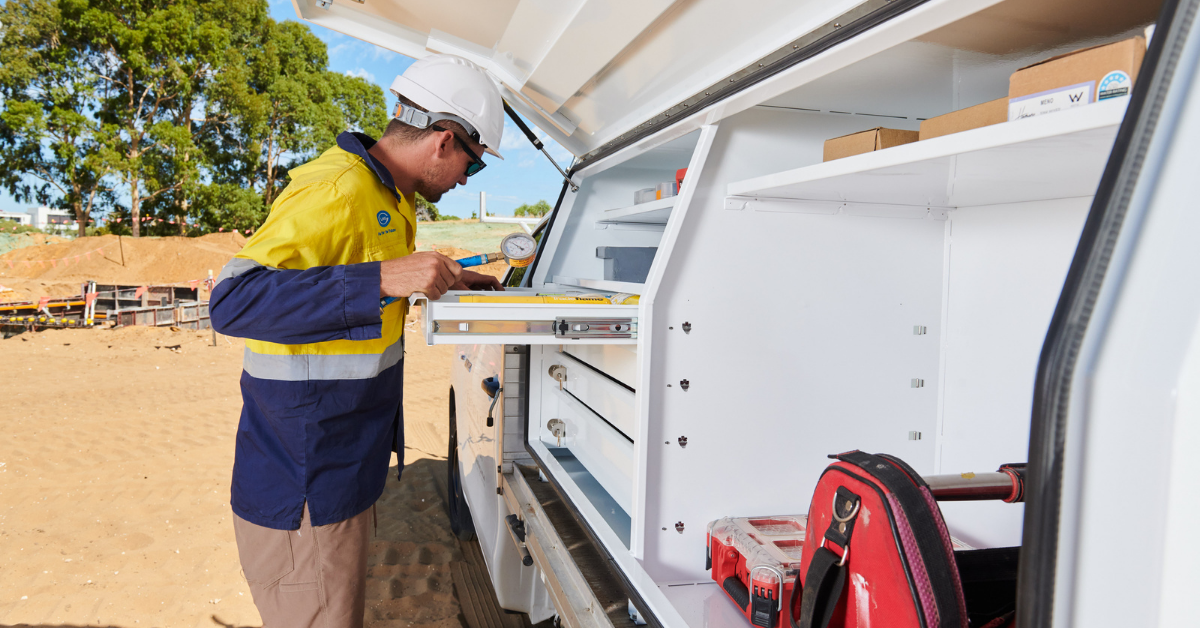 Tradesperson accessing an organised aluminium ute canopy with internal drawers, shelving and tool storage for an efficient mobile workspace.