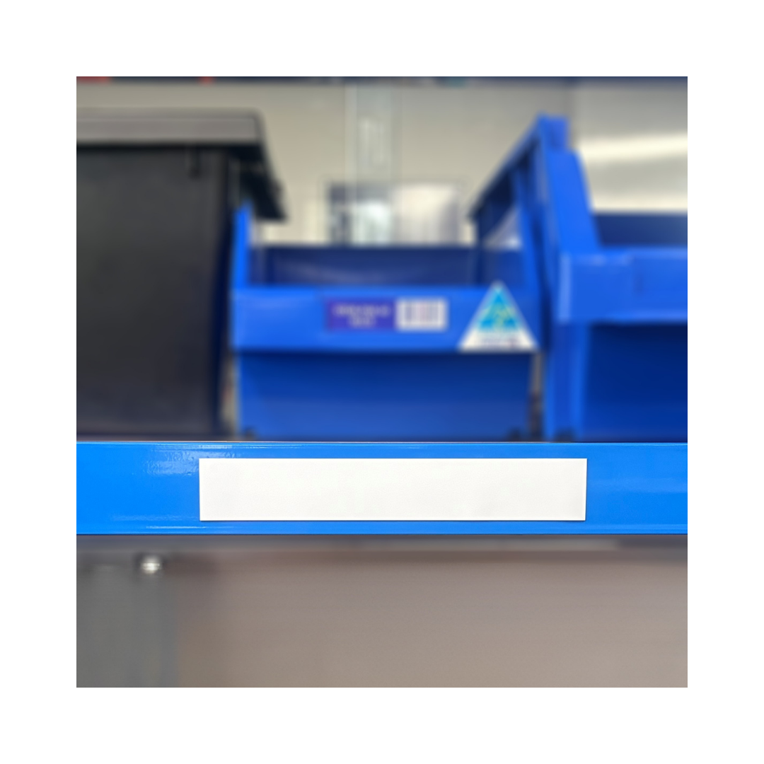 White gloss magnetic label attached to a blue longspan shelving beam for identifying warehouse shelves and storage locations.